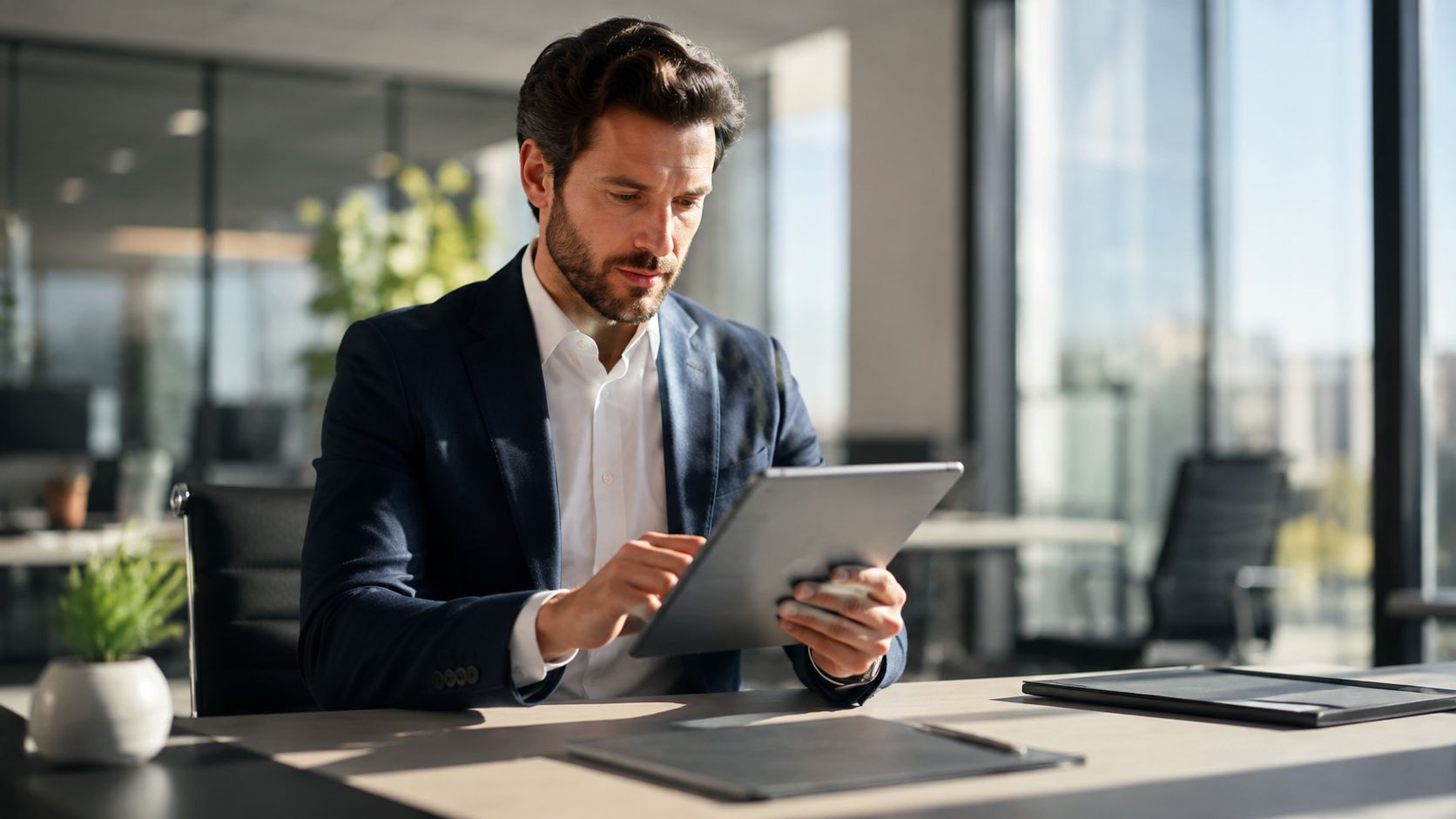 Un ejecutivo profesional analizando documentos digitales en su tableta dentro de una oficina moderna y luminosa.